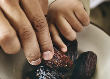 Eine Gruppe von Menschen nimmt sich Datteln aus einer Schüssel.