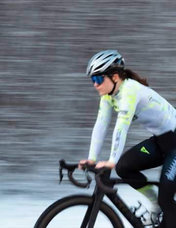 Radfahrerin des Cycling Team Ost in Bewegung mit verschwommenem Hintergrund, der die Geschwindigkeit anzeigt.